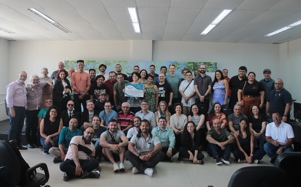 Foto colorida com mais de 50 pessoas pousando para foto durante o evento, parte delas estão em pé e outra parte centada e abaixada, para que todos aparecessem na imagem. 